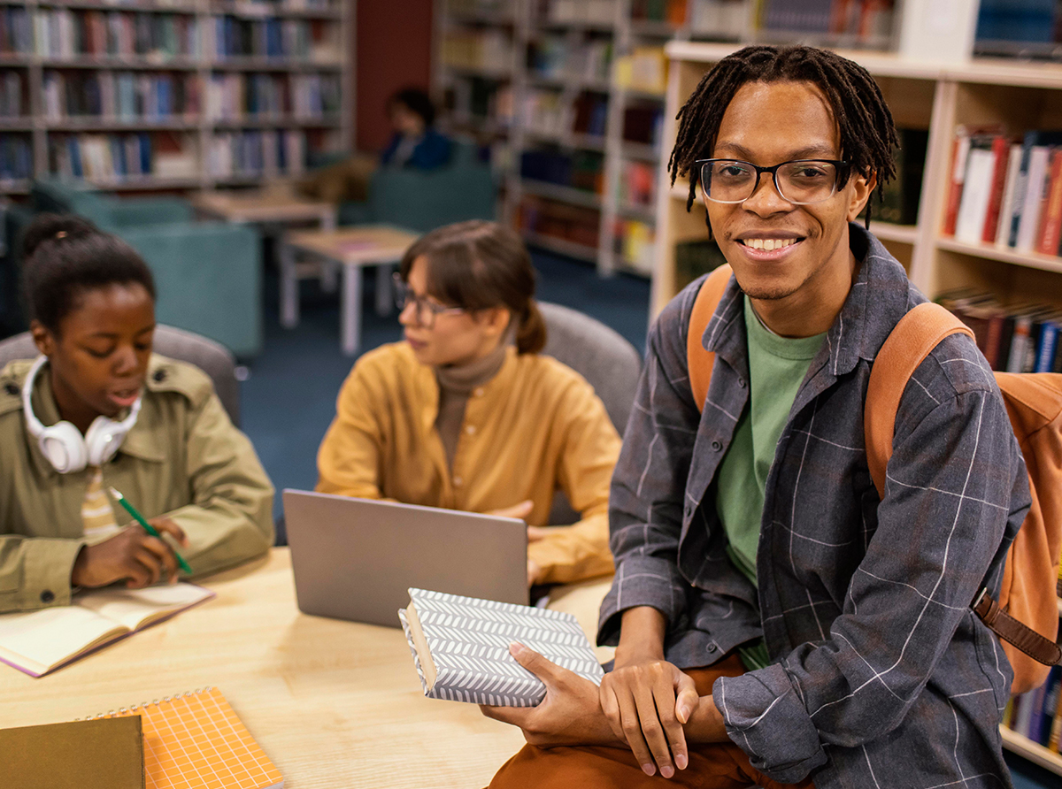 A happy student at the library, focused on academic success.