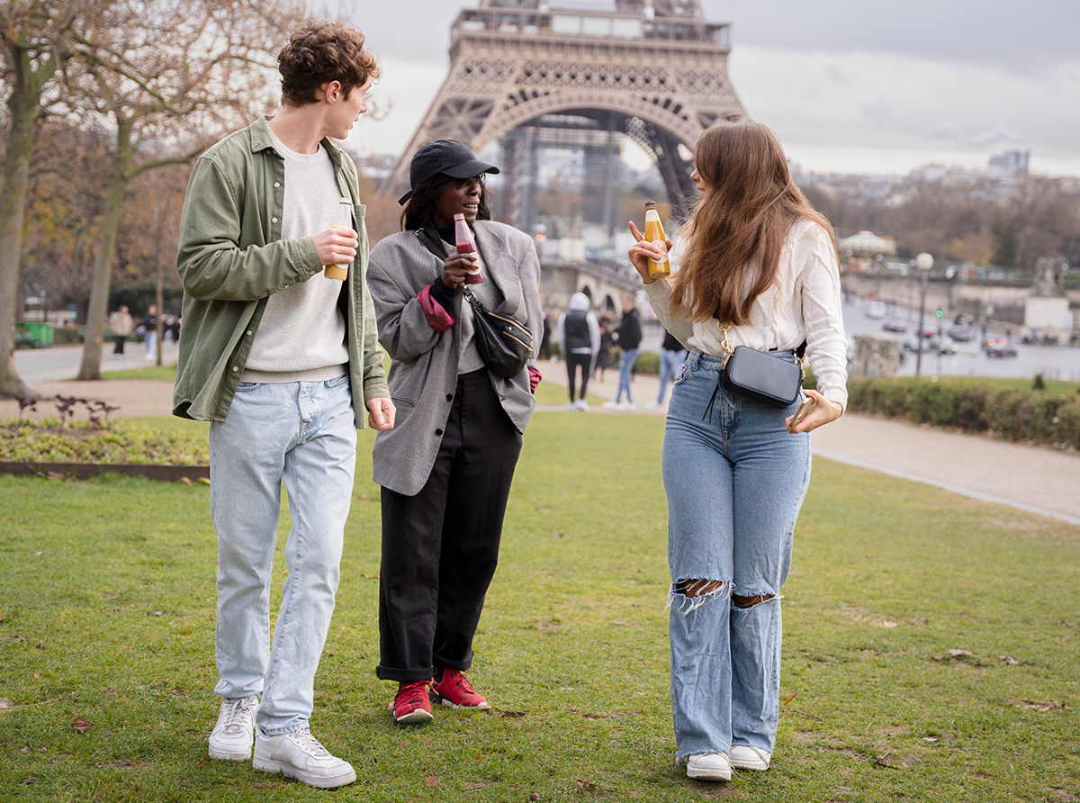 Three students walking in front of the Eiffel Tower, enjoying their academic journey.