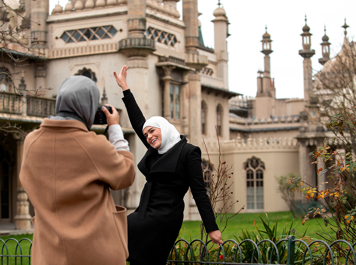 Two happy student girls, one taking a photo of the other, celebrating their academic journey.